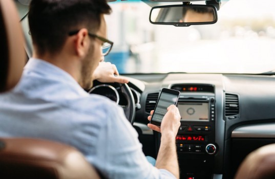 transportation concept - man using phone while driving the car