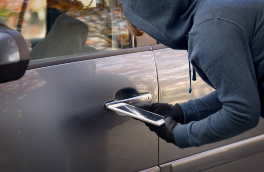 Hooded thief tries to break the car's security systems with tabl