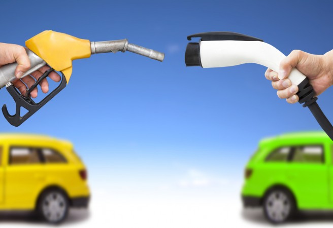 electric car and gasoline car concept. hand holding gas pump and