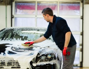 Man worker washing luxury car with sponge on a car wash