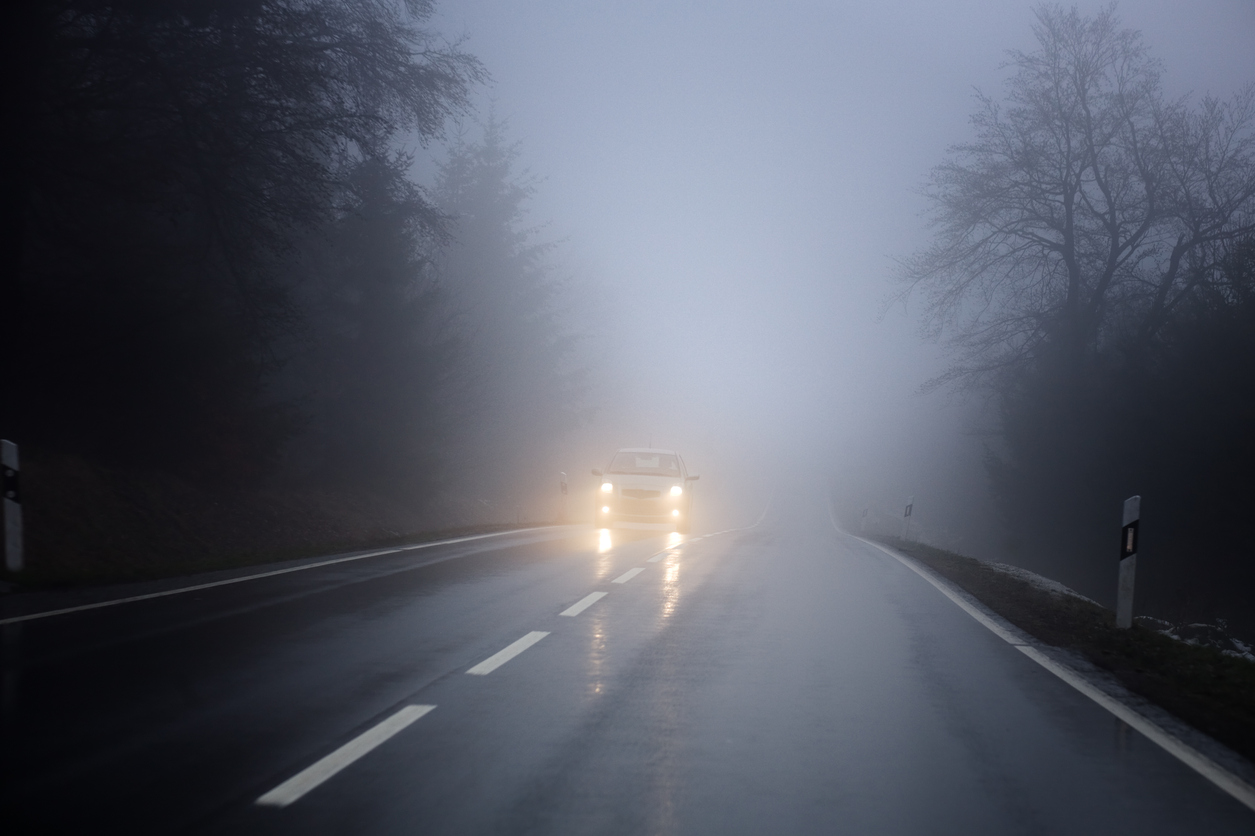 Dense fog on the country road, oncoming traffic